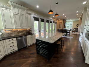 Kitchen with dark cabinets, pendant lighting, dark stone counters, recessed lighting, and backsplash