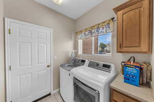Laundry room with light tile patterned floors, independent washer and dryer, and cabinet space