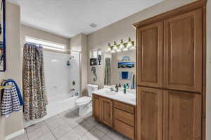 Bathroom with shower / bath combo, light tile patterned floors, vanity, and a textured ceiling