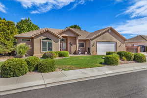 Ranch-style house featuring an attached garage, a tiled roof, stucco siding, a front lawn, and driveway