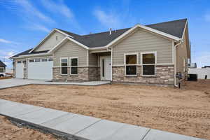 Craftsman house featuring stone siding, driveway, an attached garage, and roof with shingles