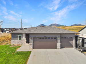 View of front facade with stone siding, a garage, roof with shingles, concrete driveway, and stucco siding
