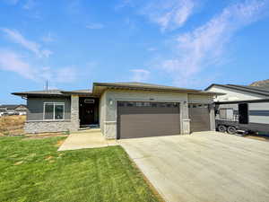 Prairie-style home featuring stucco siding, a garage, stone siding, and concrete driveway