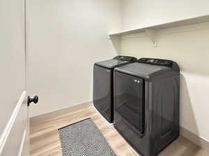 Laundry room with light wood-type flooring and washing machine and clothes dryer