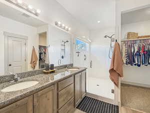Full bath featuring a walk in closet, a shower stall, and double vanity