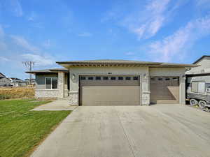 Prairie-style home with stone siding, stucco siding, concrete driveway, and a garage