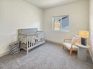 Carpeted bedroom featuring a crib and baseboards