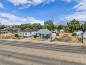 Bungalow-style house featuring a residential view, a detached garage, driveway, a shingled roof, and an outbuilding