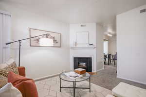 Carpeted living area with a fireplace and baseboards