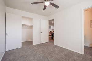 Unfurnished bedroom with a spacious closet, carpet, and a ceiling fan