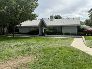 View of front of property with a front lawn, roof with shingles, and stucco siding