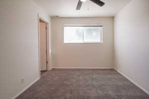 Carpeted spare room with a ceiling fan and baseboards