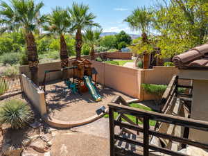 Fenced backyard featuring a playground, a mountain view, and a patio area