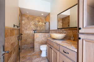 Full bathroom with tile walls, vanity, a stall shower, and wainscoting