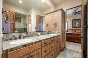 Bathroom with double vanity, tasteful backsplash, tiled shower, ceiling fan, and recessed lighting