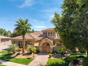 Mediterranean / spanish-style home with stucco siding, a gate, and a tiled roof