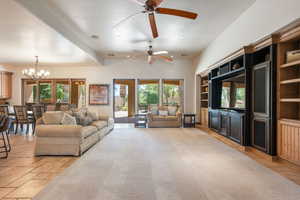 Living room featuring stone tile flooring, recessed lighting, a chandelier, and a ceiling fan