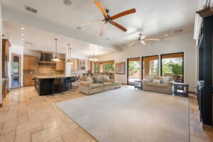Living room with a chandelier, stone tile flooring, recessed lighting, and ceiling fan