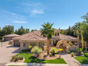 Mediterranean / spanish home featuring stucco siding, decorative driveway, a tiled roof, a gate, and an attached garage