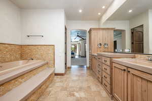 Full bathroom with double vanity, a garden tub, a ceiling fan, recessed lighting, and light stone finish flooring