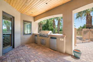 View of patio featuring area for grilling and a gate