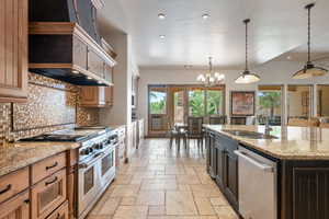Kitchen with stainless steel appliances, stone tile flooring, recessed lighting, decorative light fixtures, and light stone countertops