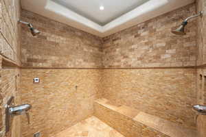 Bathroom view of tiled shower, a raised ceiling, tile walls, and recessed lighting