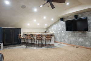 Indoor bar featuring lofted ceiling, dark cabinets, recessed lighting, ceiling fan, and light carpet