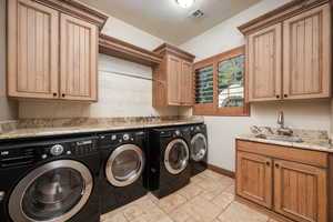 Washroom featuring washing machine and dryer, stone tile floors, and cabinet space