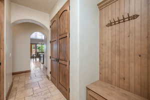 Mudroom featuring arched walkways, stone tile flooring, and a chandelier