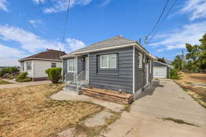 Bungalow-style house featuring a detached garage, an outdoor structure, and a shingled roof