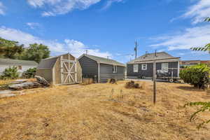Rear view of house with a storage unit, a patio area, and a shingled roof