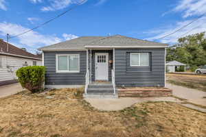 Bungalow-style house featuring roof with shingles and a front lawn