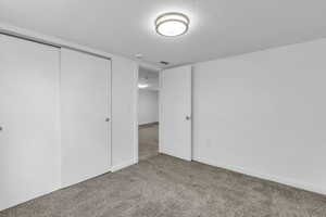 Unfurnished bedroom with a textured ceiling, carpet floors, and a closet