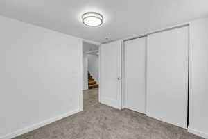 Unfurnished bedroom featuring a textured ceiling, light colored carpet, and a closet