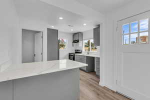 Kitchen with gray cabinetry, electric range, recessed lighting, a peninsula, and light wood finished floors