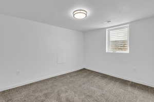 Empty room with carpet and a textured ceiling