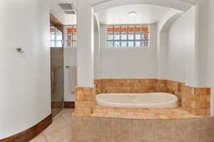 Bathroom with healthy amount of natural light, a garden tub, tile patterned flooring, and a stall shower