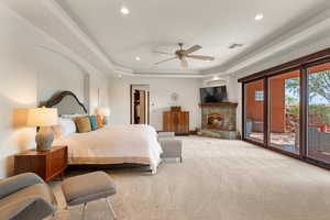 Carpeted bedroom with a tray ceiling, a spacious closet, access to exterior, recessed lighting, and a ceiling fan
