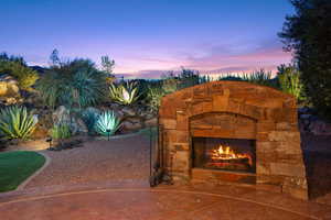 Patio terrace at dusk featuring an outdoor stone fireplace