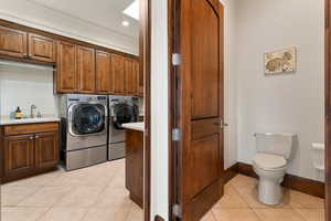Washroom featuring light tile patterned flooring, washing machine and dryer, cabinet space, and recessed lighting
