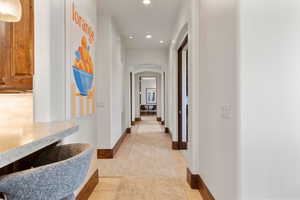 Hallway with arched walkways, recessed lighting, and light tile patterned floors