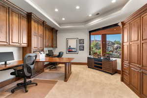 Office with a tray ceiling, recessed lighting, light colored carpet, and built in study area