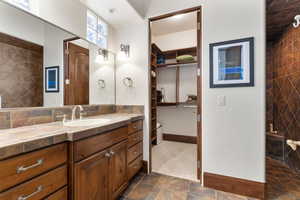 Full bath with vanity, a walk in closet, decorative backsplash, and dark tile patterned floors
