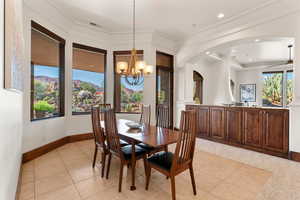 Dining room featuring light tile patterned floors, a chandelier, recessed lighting, crown molding, and arched walkways