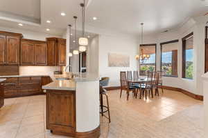 Kitchen with a kitchen bar, a peninsula, decorative light fixtures, light tile patterned floors, and tasteful backsplash