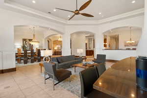Living area with a chandelier, a tray ceiling, light tile patterned floors, wainscoting, and recessed lighting