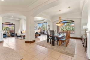 Dining space featuring light tile patterned floors, plenty of natural light, crown molding, and arched walkways