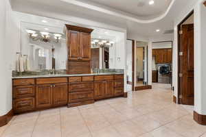 Full bathroom featuring a chandelier, light tile patterned flooring, double vanity, washer / dryer, and recessed lighting