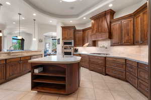 Kitchen with open shelves, ceiling fan, light tile patterned floors, pendant lighting, and a kitchen island with sink